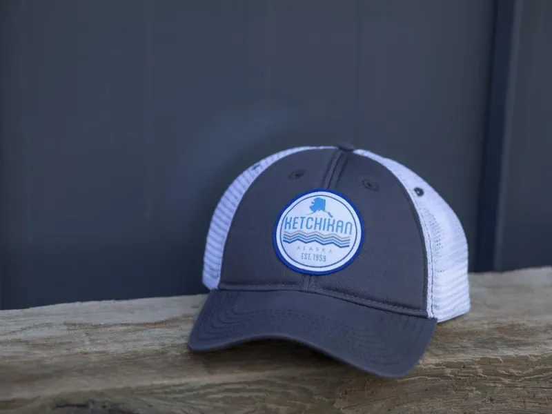 Grey and white trucker hat with blue circle Ketchikan state and waves patch